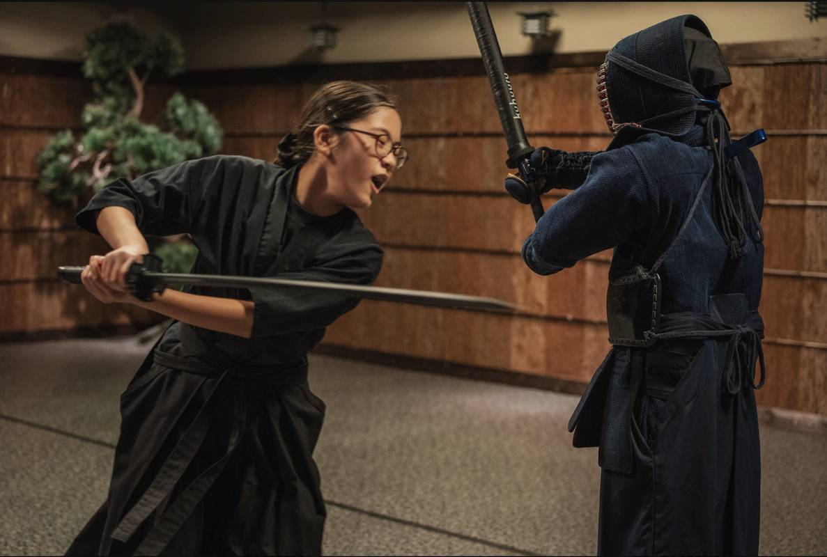 Guest delivering a full-power katana strike on the life-size samurai striking dummy in the Tokyo dojo